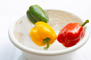 Bell pepper soaked in water. Washing fresh vegetables on white