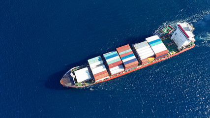 Aerial drone photo of cargo container ship guided by tug assistive boat to Mediterranean logistics...