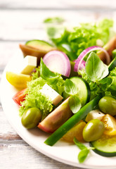 Healthy salad wwith feta cheese, green olives, cucumber, red onion, green pepper, various tomatoes and fresh basil. Close up. 