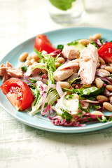 Healthy salad with tuna, cannellini bean, endive and tomatoes. Bright wwooden background. 