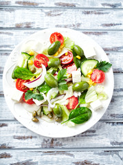 Healthy Salad with Feta Cheese, Cherry Tomatoes, Cucumber, Green Olives and Spinach. Bright wooden background. Top view.