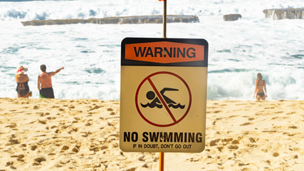 Hawaiian Beach No swimming signs, with rough seas behind