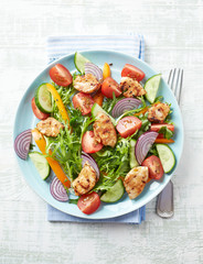 Healthy Salad with Chicken Briest, Cherry Tomatoes, Cucumber, Rocket and fresh Basil. Bright wooden background. Top view.