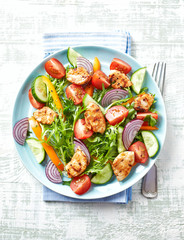 Healthy Salad with Chicken Briest, Cherry Tomatoes, Cucumber, Rocket and fresh Basil. Bright wooden background. Top view.