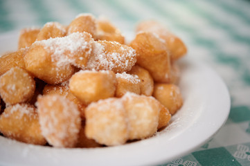 Italian dessert zeppole sugar powdered on the table with white green patterned cloth