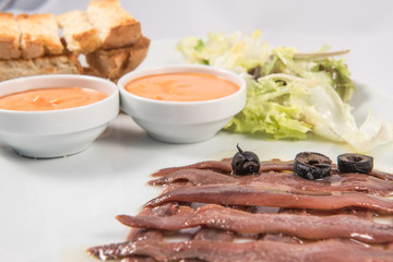 Cantabrian achoas dish with black olives, toasted bread and tomato sauce