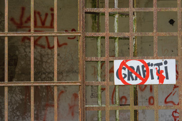 Walls with graffiti and graffiti prohibition sign 
