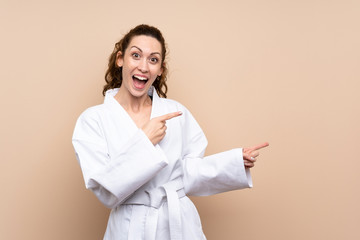 Young woman doing karate surprised and pointing side