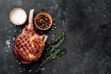 steak - beef tomahawk with spices, thyme on a stone background. with copy space for your text