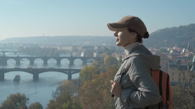 Admire the top of Prague. Girl tourist on a panoramic platform looks at the old city bridges in Europe.