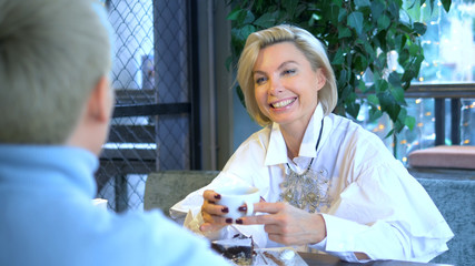 two beautiful stylish women blondes communicate sitting in a cafe