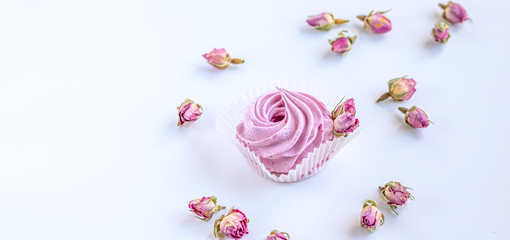 Pink fruit marshmallow and dried buds of roses on the white background. 
