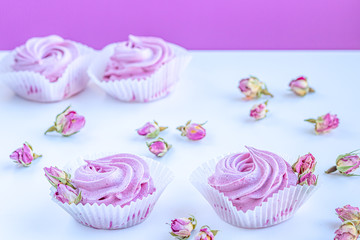 Pink fruit marshmallows and dried buds of roses on the white background. 