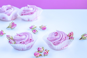 Pink fruit marshmallows and dried buds of roses on the white background. 