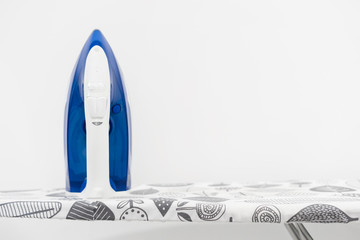 Flatiron iron blue on the ironing board in front of the white wall background