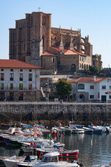 Fototapeta na wymiar Port in Castro Urdiales, Cantabria; Spain. Image of colored boats and in the background the Church is Santa Maria de la Asunción. Image.