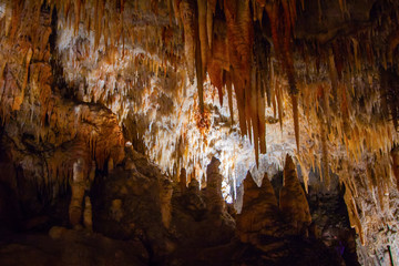 A cave with many stalagmite and stalactites. High contrast - dark foreground and well lit background. Yarrangobilly Caves, Kosciuszko National Park, NSW, Australia.