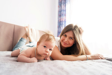 Mother with her newborn son lay on the bed in the rays of sunlight coming out of the window 