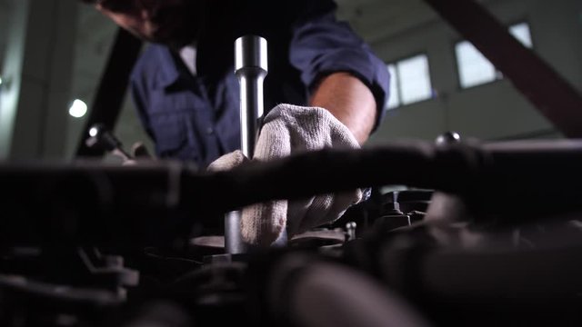 Closeup of repairman's hands working on replacement of oil filter in car repair service. Auto repair specialist using wrench while going to change oil filter during vehicle maintenance in car workshop