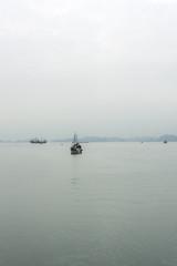 Traditional Vietnamese Sailing Fishing Boat in Bai Tu Long Bay in Halong Bay Vietnam on a Cloudy Day