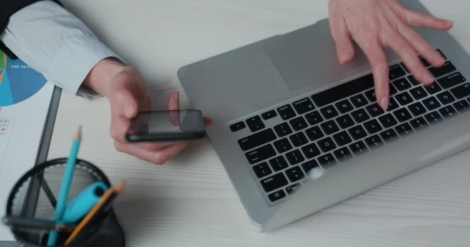 Businesswoman hands are typing the data on laptop keyboard. Professional traider is pushing the bottons, checking rates on graph