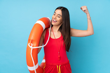 Lifeguard woman over isolated blue background with lifeguard equipment and celebrating a victory