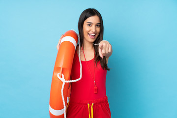 Lifeguard woman over isolated blue background with lifeguard equipment and points finger at you - obrazy, fototapety, plakaty