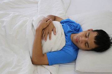 A cute Asian young man is sleeping on a bed.