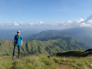 Fototapeta premium Młody Azjata stoi na dużej skale w górach zimą, ciesząc się naturą