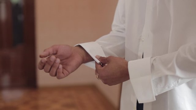 Handsome groom man fixes his cuffs on a jacket with cufflinks. Businessman