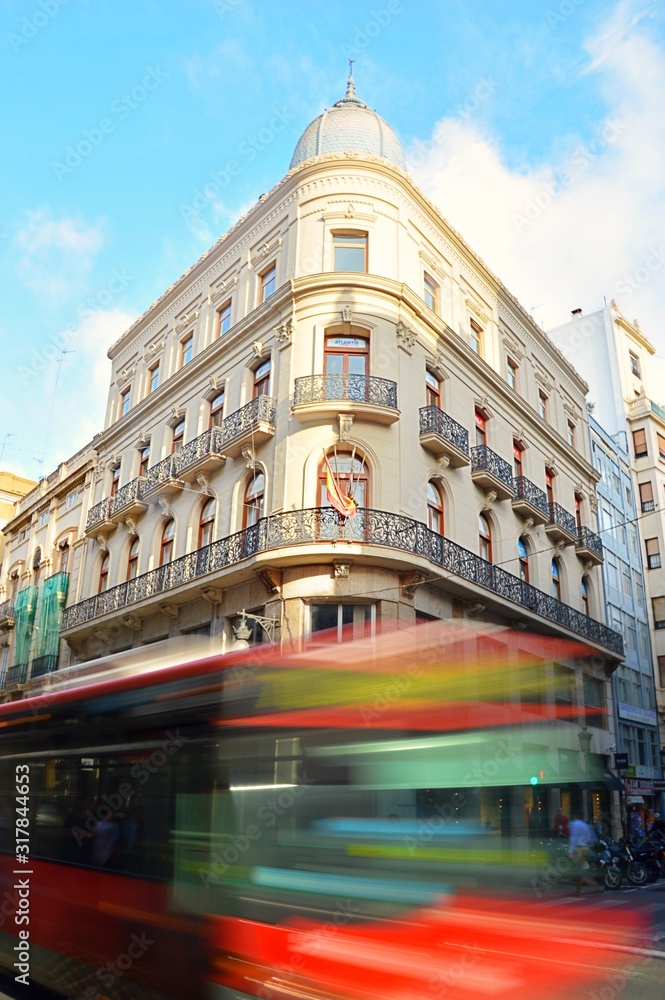 Poster Beautiful view of a white building in Valencia, Spain with a red bus in motion in the foreground