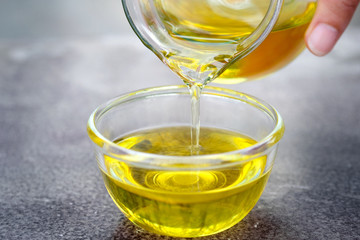 Pouring olive oil in the a glass bowl at stone kitchen and inside green garden view. Prepare for cooking concept. Healthcare and Beauty Concept.