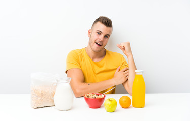 Young blonde man having breakfast making strong gesture