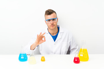 Young scientific with lots of laboratory flask showing an ok sign with fingers