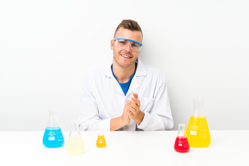 Young scientific with lots of laboratory flask applauding