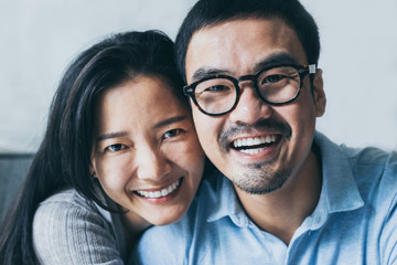 couple love concept.asian sweet lover man and women smiling taking a selfie sitting on sofa at home on anniversary hug in embrance each other.photo of people smile enjoy  Beautiful romantic time