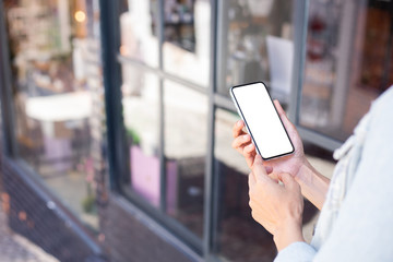 Mockup image blank white screen cell phone.woman hand holding texting using mobile on street at outdoor.background empty space for advertise text.people contact marketing business,technology