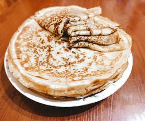 Appetizing fried pancakes with honey on a white plate.