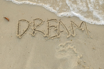 A selective focus picture of dream words on sandy beach.