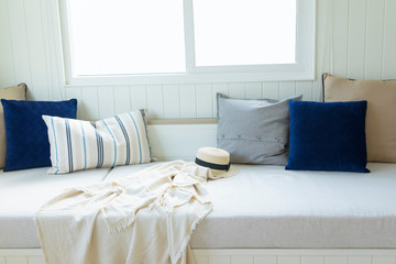 white sofa bed nook with comfortable pillows and blanket by the window.