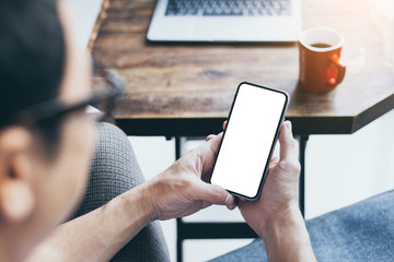 Mockup image blank white screen cell phone.man hand holding texting using mobile on desk at home office.background empty space for advertise text.people contact marketing business,technology