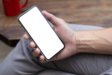 Mockup image blank white screen cell phone.man hand holding texting using mobile on desk at home office.background empty space for advertise text.people contact marketing business,technology