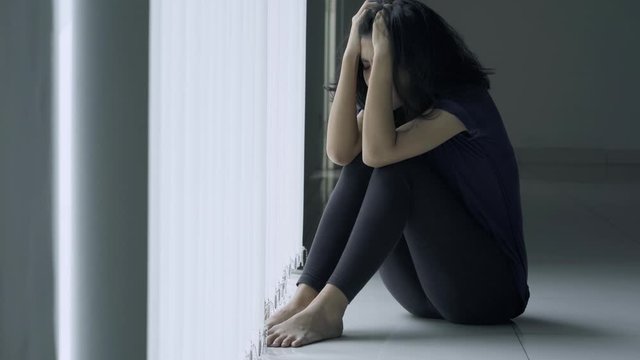 Anorexic woman looks depressed near the window