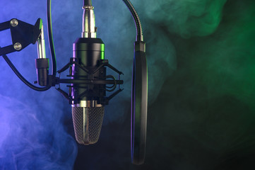 studio condenser microphone with pop-filter and anti-vibration mount with backlight, color purple and green smoke. Side view with space