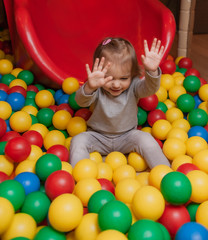 Fototapeta na wymiar Little Joyful girl in the pool with colorful balls. Children's entertainment center