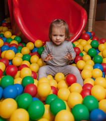 Fototapeta na wymiar Little Joyful girl in the pool with colorful balls. Children's entertainment center
