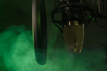 Close up studio condenser microphone on stand and anti-vibration mount. Live recording with colored...