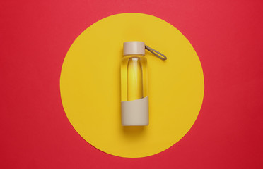 Bottle of water for sports and outdoor activities on red yellow circle background. Top view