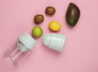 Plastic manual juicer and tropical fruits on pink pastel  background. Healthy food concept. Freshly squeezed juices. Top view