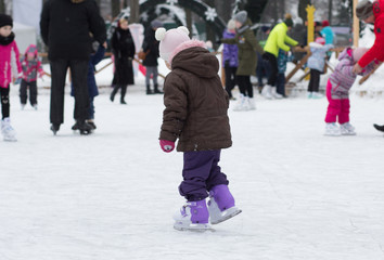 Side view of caucasian child of three years old skating on the rink in wintertime